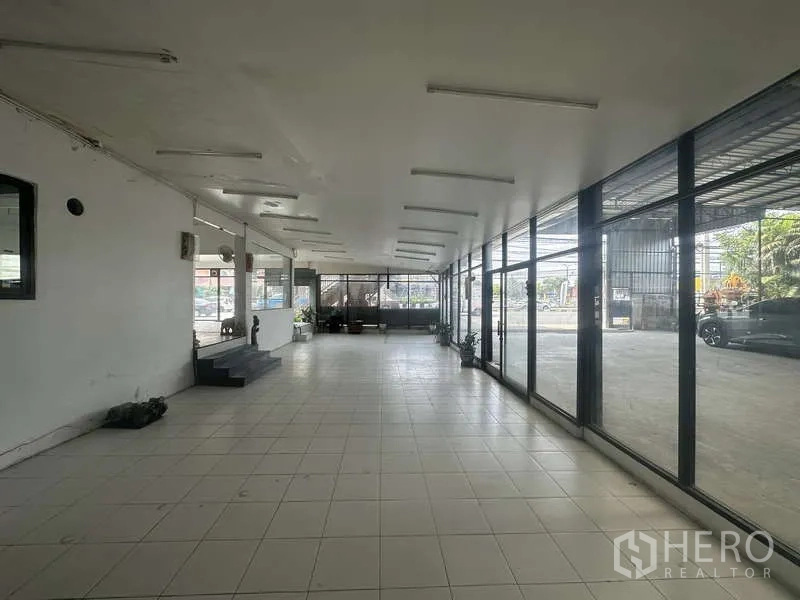 Warehouse for rent in Pak Kret, Nonthaburi - Front showroom space with tiled floor, ceiling lights, and full-height glass along the street.