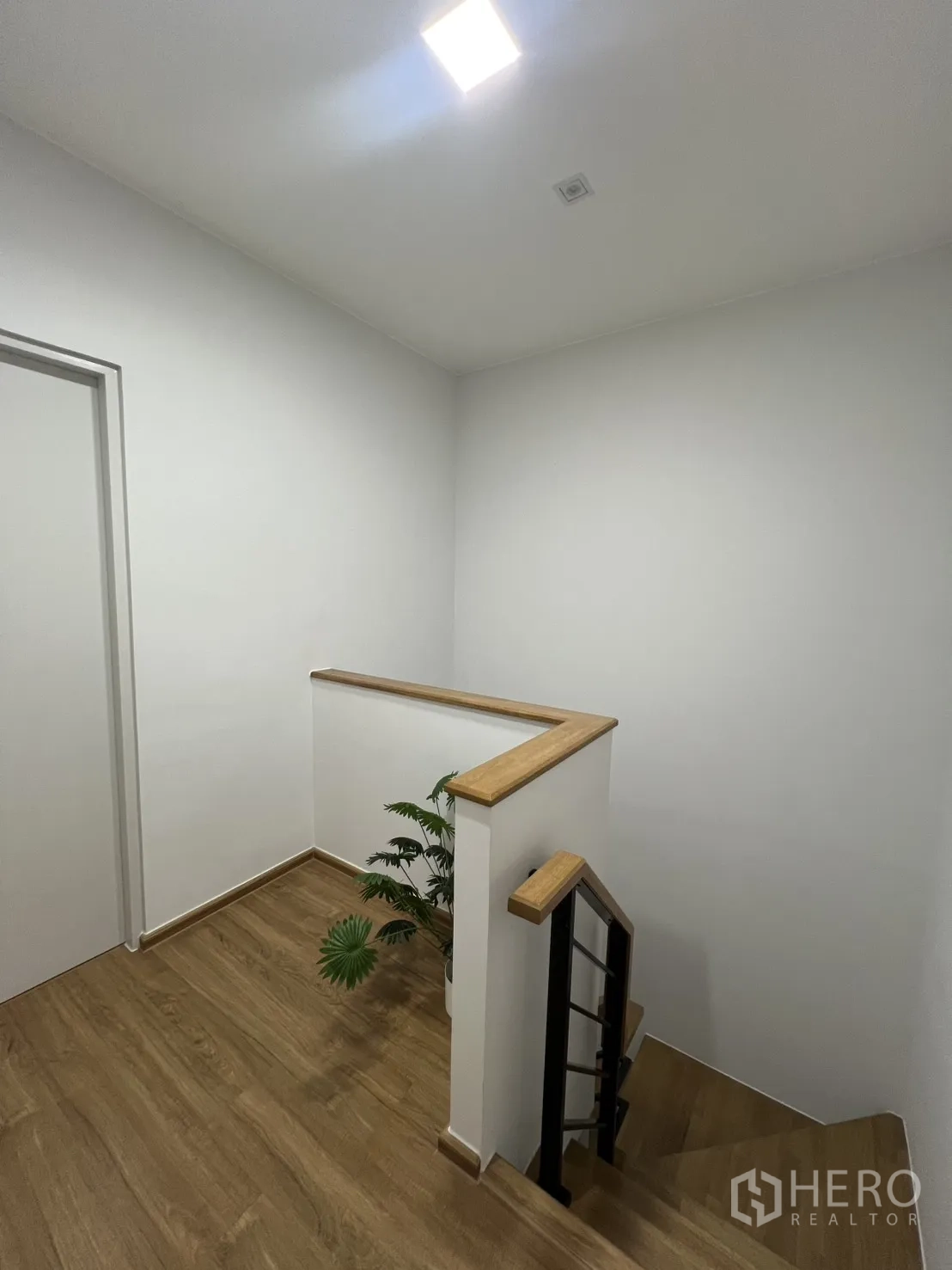 Townhouse for rent in Bang Phli, Samut Prakan - Staircase view with black metal balustrade and plant at the landing.