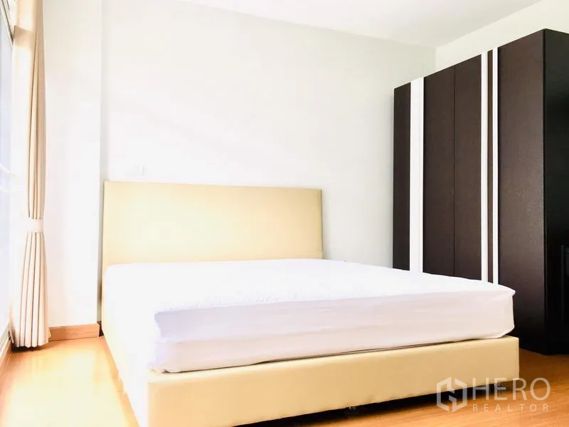 联排别墅 出租在Prawet, Bangkok - 次卧带床与深色大衣柜，落地窗通风采光佳。