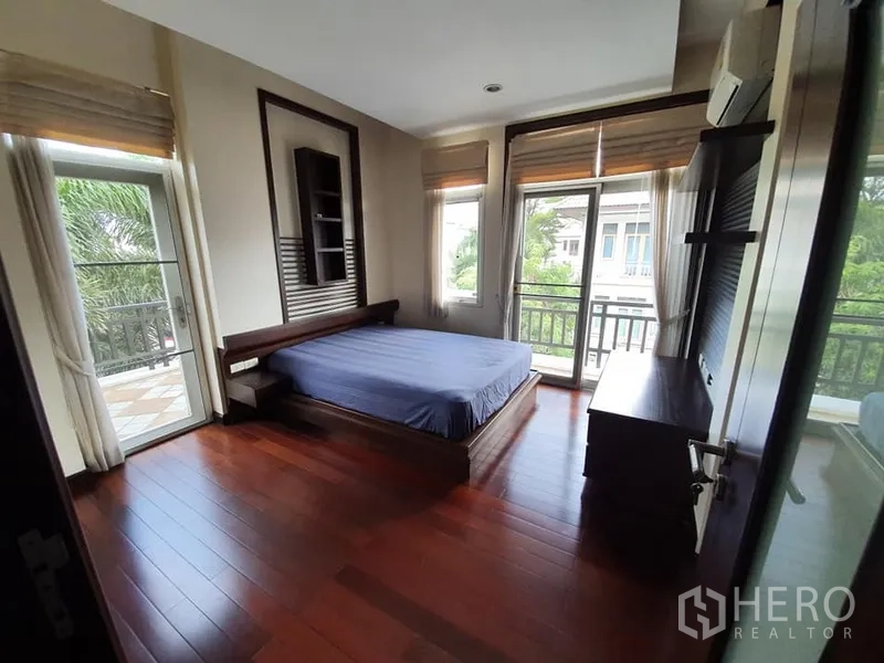 Detached House for rent in Wang Thonglang, Bangkok - Bedroom with wood floors, corner windows and door opening to a balcony with neighborhood views.