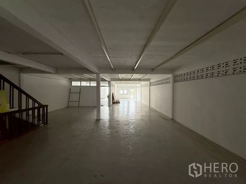 อาคารพาณิชย์ ให้เช่า - พื้นที่ทำงานยาวโล่ง ผนังสีขาว หน้าต่างเตี้ย พร้อมบันไดด้านหลัง
