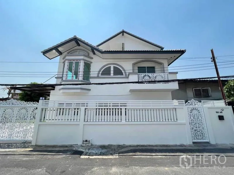 Detached House for sale in Bang Bon, Bangkok - Front façade of a two‑storey white house with balconies and a decorative perimeter fence.