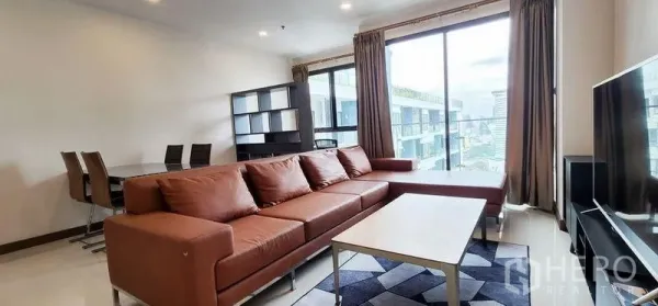 Condominium for rent - Bright living room with an L-shaped leather sofa, coffee table, TV console and floor-to-ceiling windows with city views.