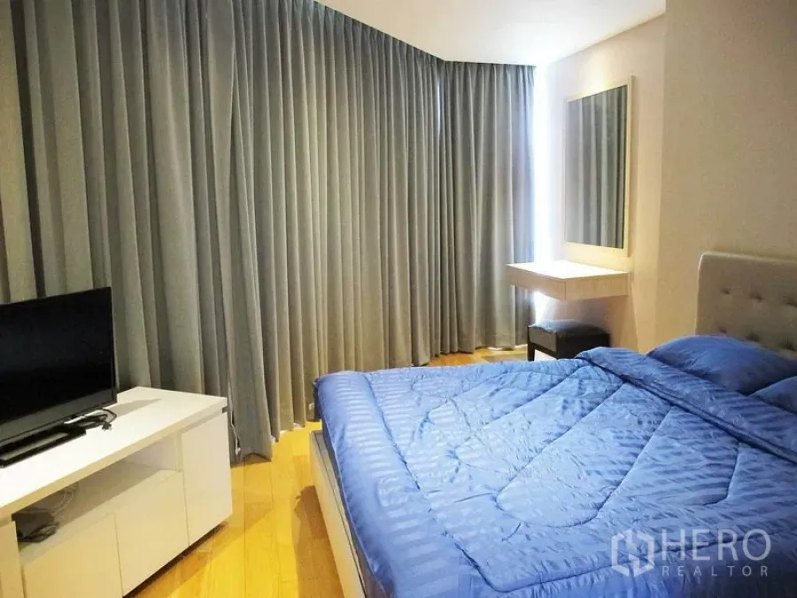 คอนโด ให้เช่าในWatthana, Bangkok - ห้องนอนใหญ่ ผ้าปูเตียงสีน้ำเงิน ม่านสูงจรดเพดาน กระจกเงาและตู้วางทีวี