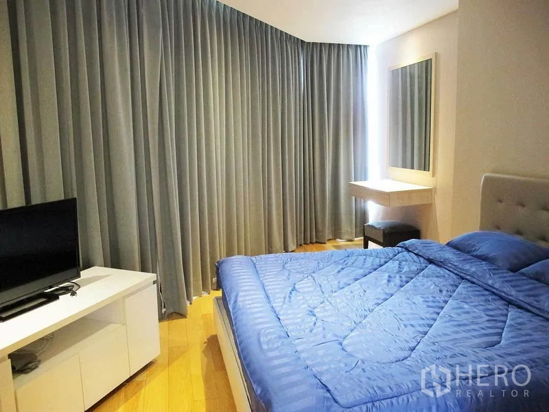 คอนโด ให้เช่าในWatthana, Bangkok - ห้องนอนใหญ่ ผ้าปูเตียงสีน้ำเงิน ม่านสูงจรดเพดาน กระจกเงาและตู้วางทีวี