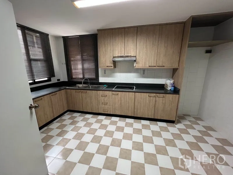 公寓 出租在Watthana, Bangkok - 独立厨房，木柜体、黑色台面、抽油烟机与棋盘格地砖。