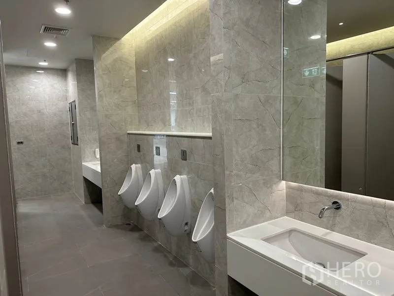 Office Space for rent in Ratchathewi, Bangkok - Modern men’s restroom with stone-look tiles, urinals and an integrated sink.