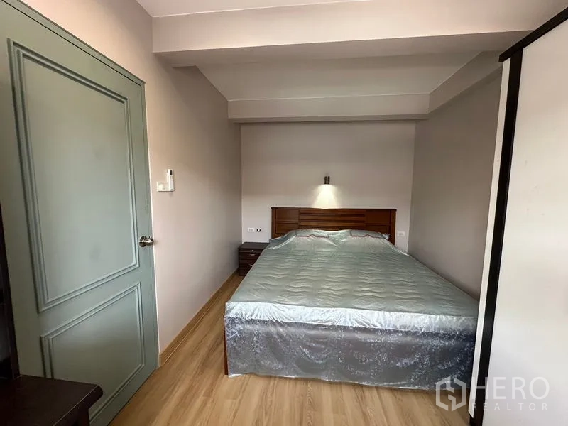 ทาวน์เฮาส์ ให้เช่าในPhra Khanong, Bangkok - ห้องนอนหลักพร้อมเตียงคู่ พื้นลามิเนต โต๊ะข้างเตียง และไฟติดผนัง