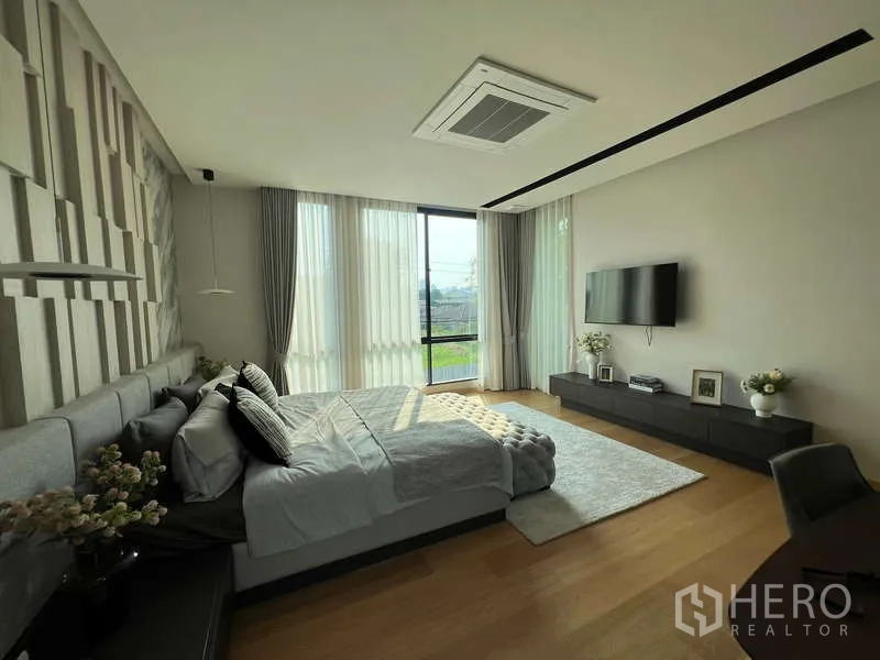 Detached House for sale in Suan Luang, Bangkok - Primary bedroom with large windows, wall-mounted TV and wood floors