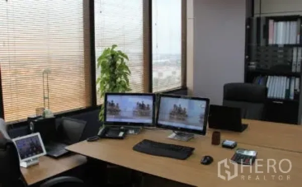 สำนักงาน ให้เช่าในBang Na, Bangkok - มุมทำงานสมัยใหม่พร้อมจอคู่ หน้าต่างบานใหญ่มีมู่ลี่ วิวเมือง และชั้นวางแฟ้มในสำนักงานบางนา.