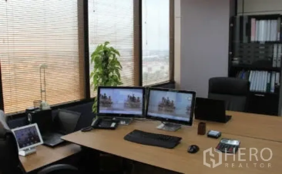 สำนักงาน ให้เช่าในBang Na, Bangkok - มุมทำงานสมัยใหม่พร้อมจอคู่ หน้าต่างบานใหญ่มีมู่ลี่ วิวเมือง และชั้นวางแฟ้มในสำนักงานบางนา.