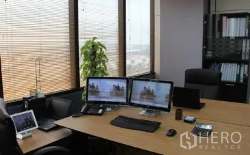 สำนักงาน ให้เช่าในBang Na, Bangkok - มุมทำงานสมัยใหม่พร้อมจอคู่ หน้าต่างบานใหญ่มีมู่ลี่ วิวเมือง และชั้นวางแฟ้มในสำนักงานบางนา.