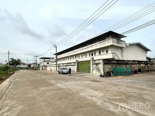Warehouse for rent in Bang Khun Thian, Bangkok - Wide concrete road and gated frontage in front of the warehouse compound.