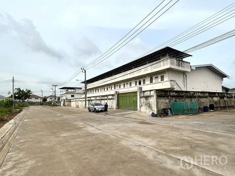 Warehouse for rent in Bang Khun Thian, Bangkok - Wide concrete road and gated frontage in front of the warehouse compound.