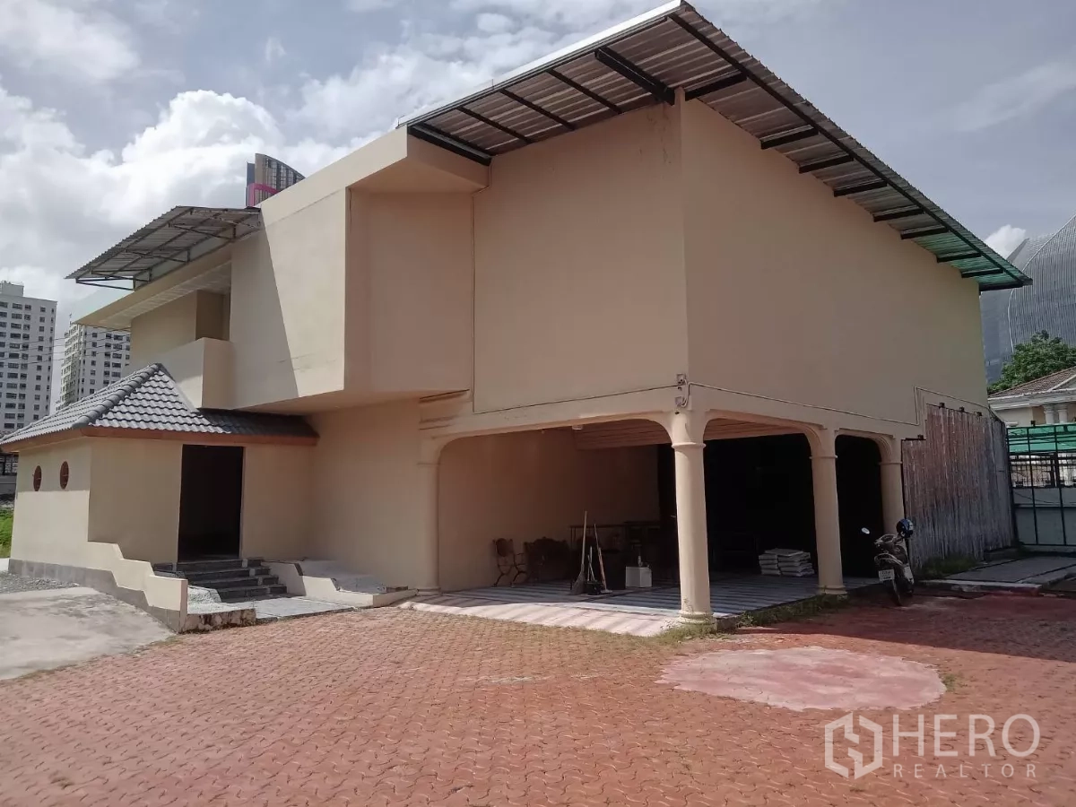 独立式住宅 出租在Phaya Thai, Bangkok - 两层主楼立面，带有覆盖车棚和瓦屋顶。