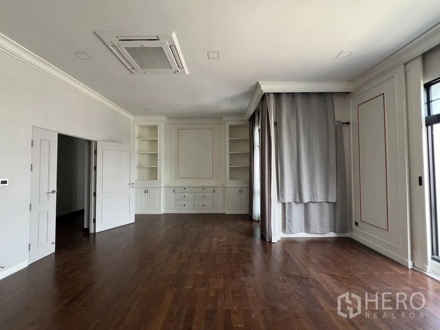 Detached House for rent or sale in Prawet, Bangkok - Expansive room with built-in cabinets, wall panels and wood floors.