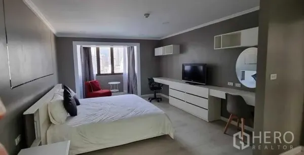 公寓 出租在Khlong Toei, Bangkok - 大卧室配双人床、电视柜、长工作台与窗边休闲区。