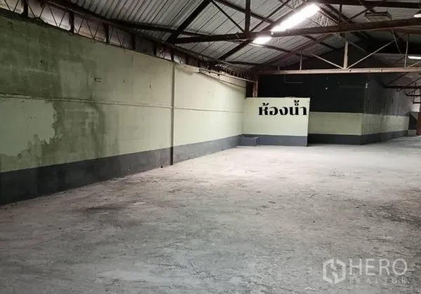 货栈 出租在Bang Khen, Bangkok - 开阔仓库区，钢桁架屋顶与粉刷墙面，标示清晰的洗手间。