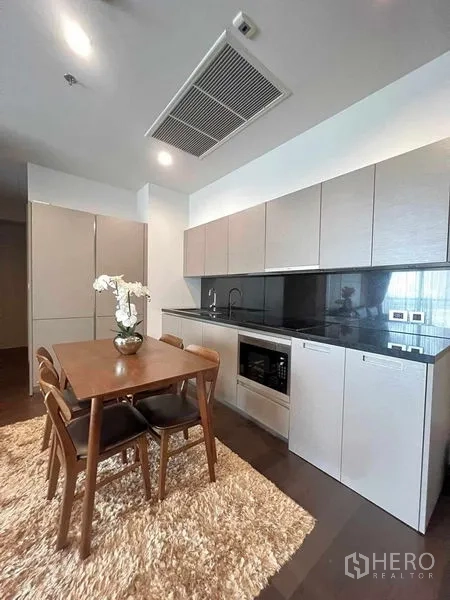 คอนโด ให้เช่าหรือขายในWatthana, Bangkok - ครัวโมเดิร์น เคาน์เตอร์หินสีดำ ตู้บิวท์อิน พร้อมโต๊ะอาหารไม้บนพรมขนฟู