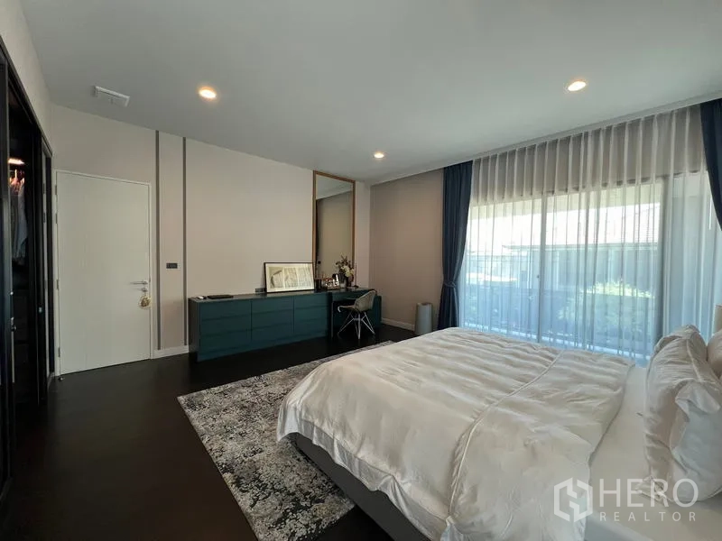 Detached House for rent in Bang Kapi, Bangkok - Master bedroom opposite wall featuring a long built-in dresser and glass doors to the balcony.