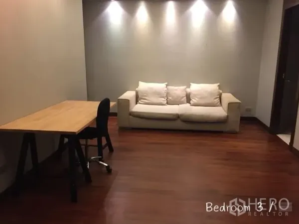 公寓 出租在Sathon, Bangkok - 多功能房，木质书桌与米色沙发，射灯墙面。