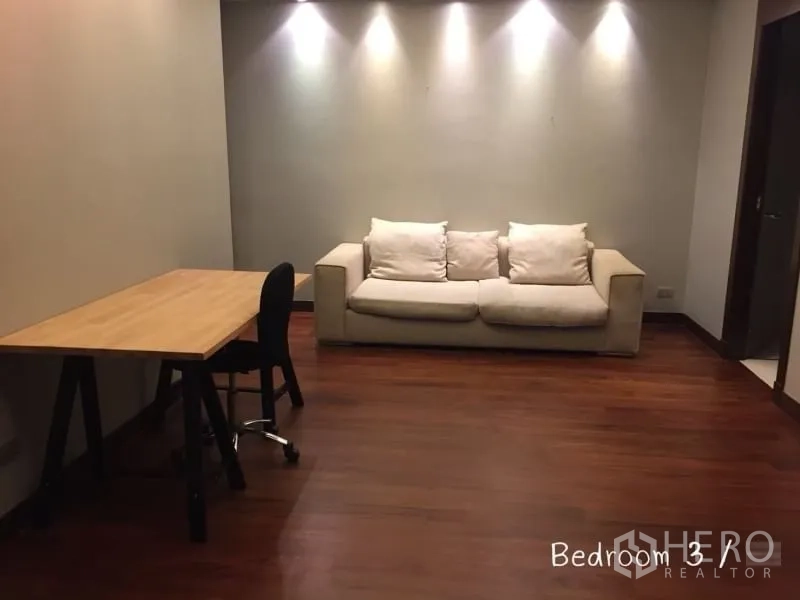 公寓 出租在Sathon, Bangkok - 多功能房，木质书桌与米色沙发，射灯墙面。