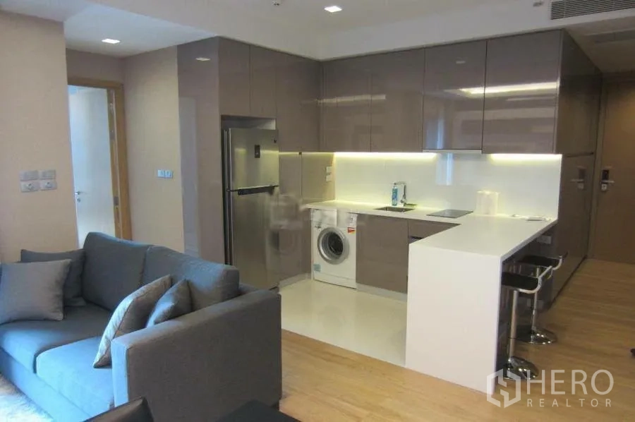 คอนโด ให้เช่าในWatthana, Bangkok - ครัวรูปตัวแอลสมัยใหม่ ตู้บิวท์อินเงา เคาน์เตอร์บาร์ควอตซ์ ตู้เย็น และเครื่องซักผ้าในห้อง ติดกับพื้นที่นั่งเล่น