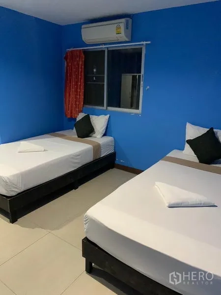 พื้นที่ขายปลีก ให้เช่าในKhlong Toei, Bangkok - ห้องเตียงเดี่ยวสองเตียง ผนังสีน้ำเงิน แอร์และหน้าต่างมีผ้าม่าน