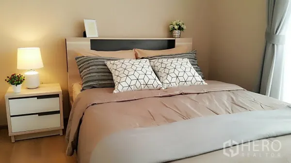 คอนโด ให้เช่าหรือขายในKhlong Toei, Bangkok - ห้องนอนใหญ่โทนอบอุ่น เตียงคู่ หมอนลายเรขาคณิต และโคมไฟหัวเตียง