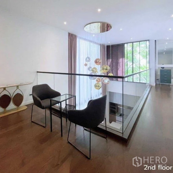Detached House for rent in Bang Kapi, Bangkok - Mezzanine seating area with glass balustrade and decorative chandelier.