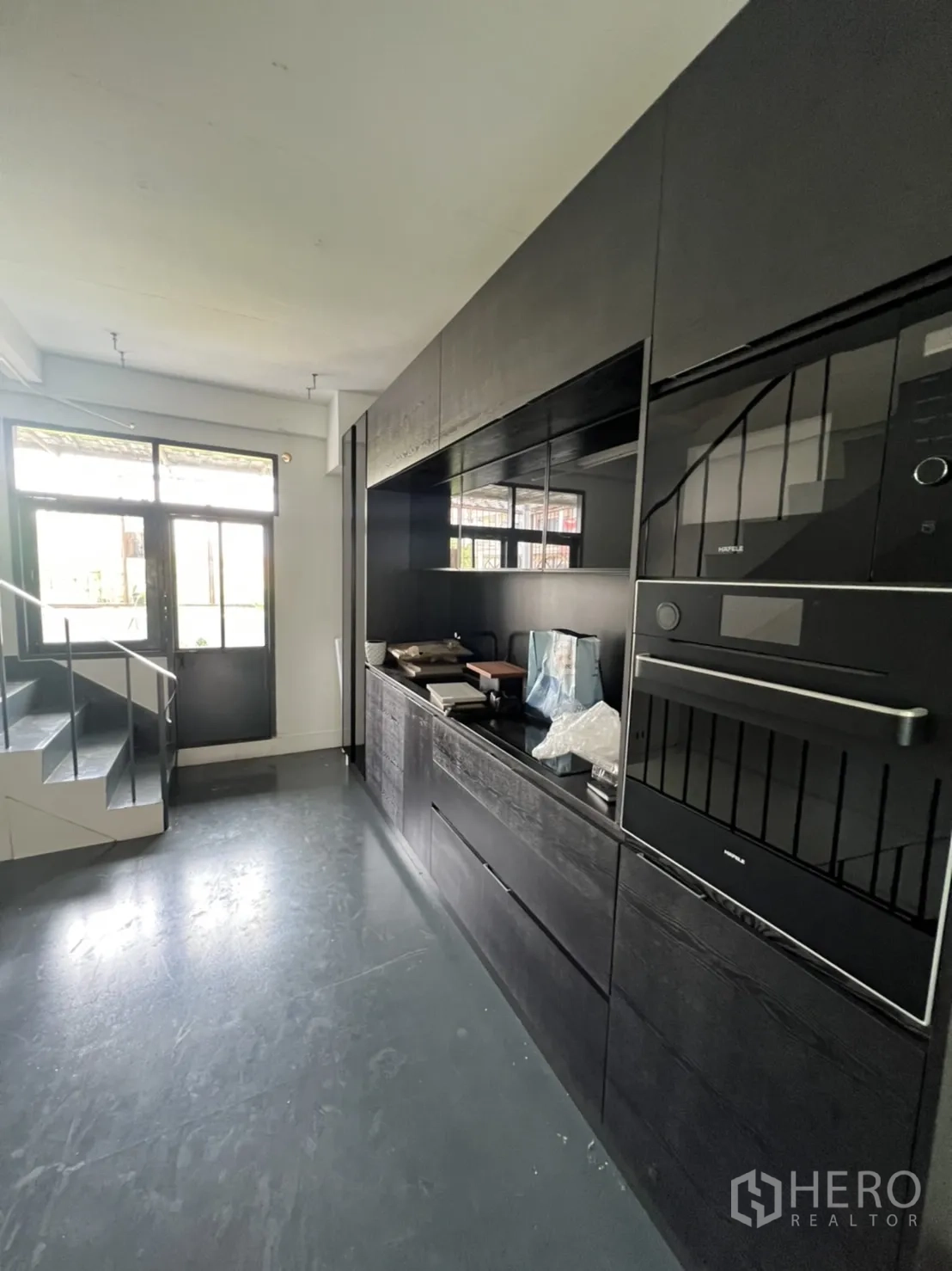 店屋 出租或出售在Watthana, Bangkok - 入口旁黑色一体式茶水间橱柜与嵌入式烤箱。