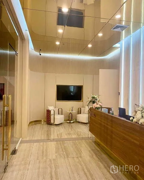 Office Space for rent in Huai Khwang, Bangkok - Reception area with wooden front desk, marble-look flooring and gold mirrored ceiling.