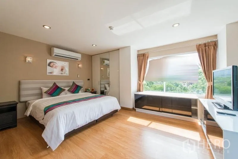 คอนโด ให้เช่าในKhlong Toei, Bangkok - ห้องนอนสว่าง เตียงคิงไซส์ หมอนสีสันสด ตู้เสื้อผ้าบิวท์อิน และวิวสวน