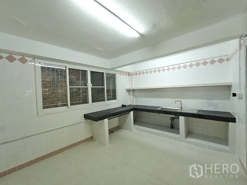 店屋 出租 - 宽敞泰式厨房，L形台面、水槽与窗户。