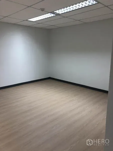 Office Space for rent in Watthana, Bangkok - Corner office room with fluorescent lighting, white walls and light wood flooring.