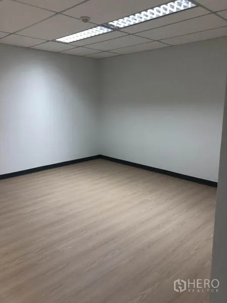 Office Space for rent in Watthana, Bangkok - Corner office room with fluorescent lighting, white walls and light wood flooring.