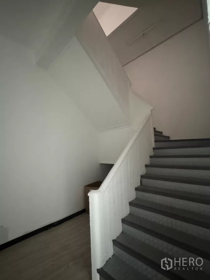 Shophouse for rent in Samphanthawong, Bangkok - Interior staircase with dark steps and white walls.
