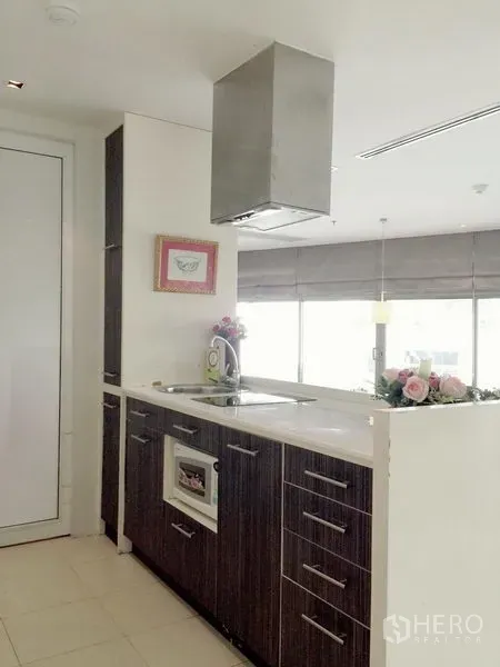 คอนโด ให้เช่าในKhlong Toei, Bangkok - ครัวแบบเปิด ตู้ลายไม้ เคาน์เตอร์สีขาว และฮูดดูดควันสแตนเลส