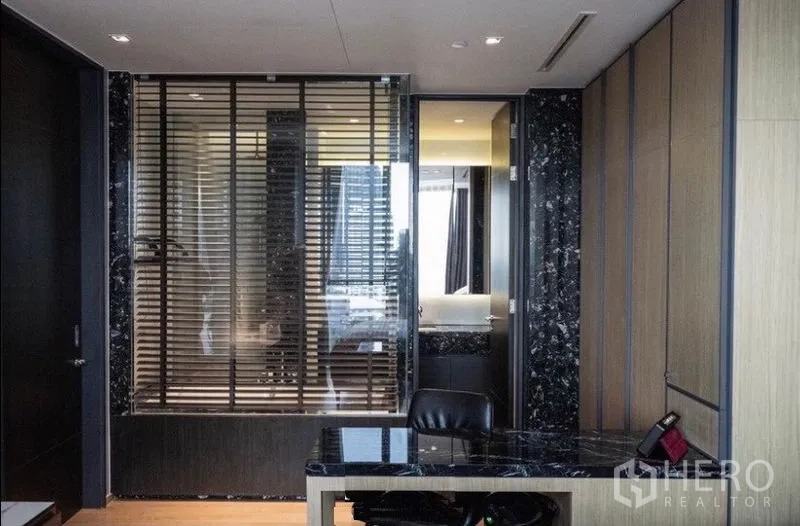 公寓 出租在Khlong Toei, Bangkok - 黑色大理石书桌，透窗可见带百叶的卫浴。