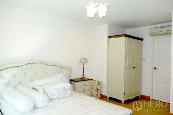 คอนโด ให้เช่าหรือขายในWatthana, Bangkok - ห้องนอนที่สองมีเตียงหัวเบาะ โต๊ะข้างเตียง ตู้เสื้อผ้า และเครื่องปรับอากาศบนพื้นไม้สีอ่อน