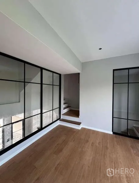 联排别墅 出租或出售在Prawet, Bangkok - 多功能房，木地板与黑框玻璃墙