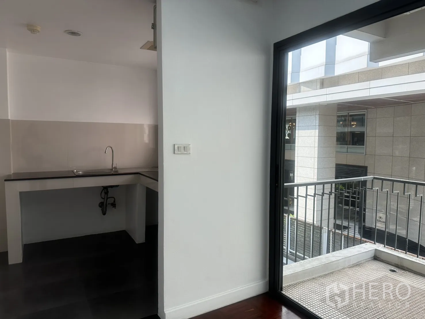 办公室 for rent in Watthana, Bangkok - 茶水间入口与阳台相邻，可见滑门与金属栏杆。