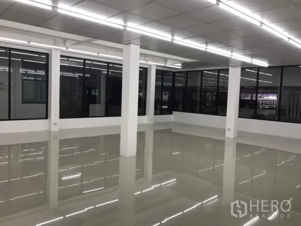 Office Space for rent in Chatuchak, Bangkok - Corner view of spacious office with white columns, black-framed windows and reflective floors.
