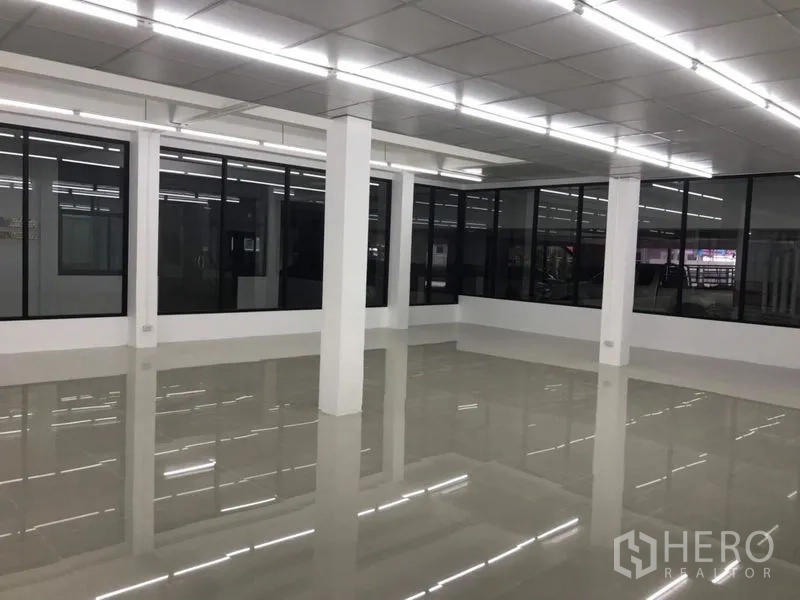 Office Space for rent in Chatuchak, Bangkok - Corner view of spacious office with white columns, black-framed windows and reflective floors.