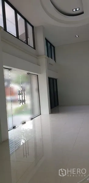 零售空间 出租在Chatuchak, Bangkok - 明亮的双层挑高零售大厅，白色亮面地砖与磨砂玻璃双扇门。