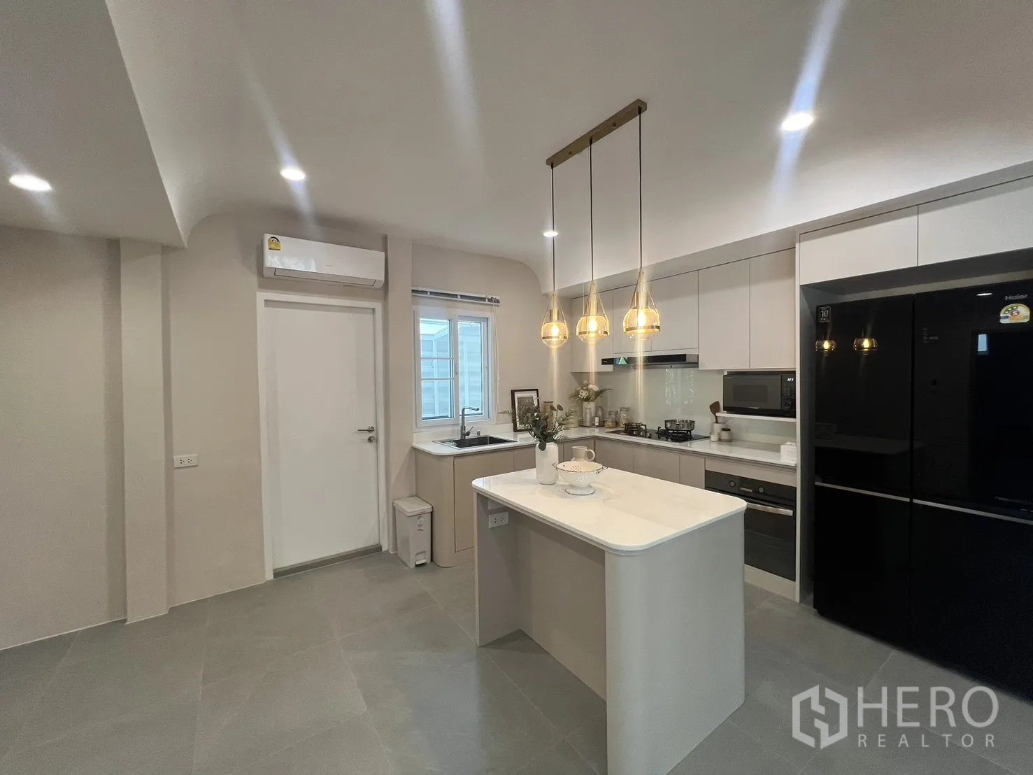 独立式住宅 出租在Mueang Samut Prakan, Samut Prakan - 厨房与客厅相连，中岛与吊灯点缀。