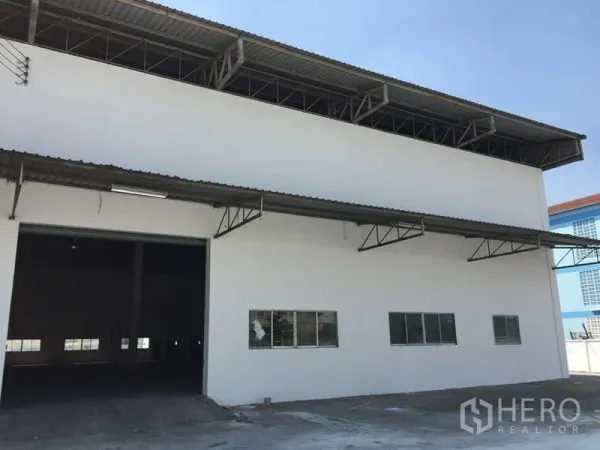 Factory for rent in Bang Bo, Samut Prakan - Factory exterior with high steel roof, loading bay canopy and wide driveway.