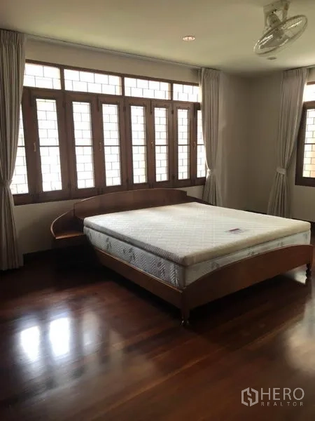 Detached House for rent in Watthana, Bangkok - Bedroom with large windows, curtains and a bed on hardwood flooring.