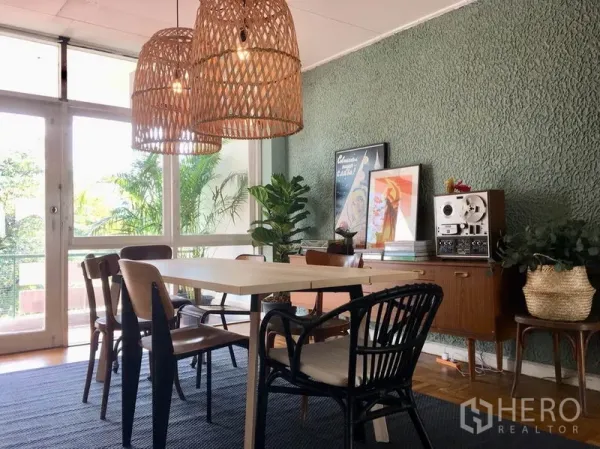 Apartment for rent in Khlong Toei, Bangkok - Sunlit dining room with textured green feature wall, mid-century sideboard, and large windows.