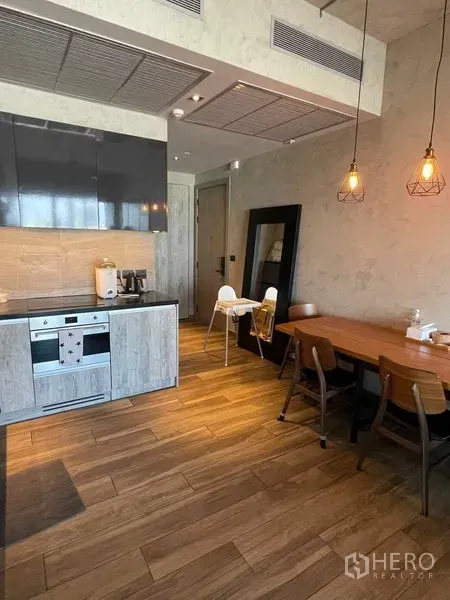 คอนโด ให้เช่าหรือขายในWatthana, Bangkok - ครัวเปิดพร้อมเตาอบบิวท์อิน พื้นไม้ และโต๊ะทานอาหารใต้โคมไฟห้อย